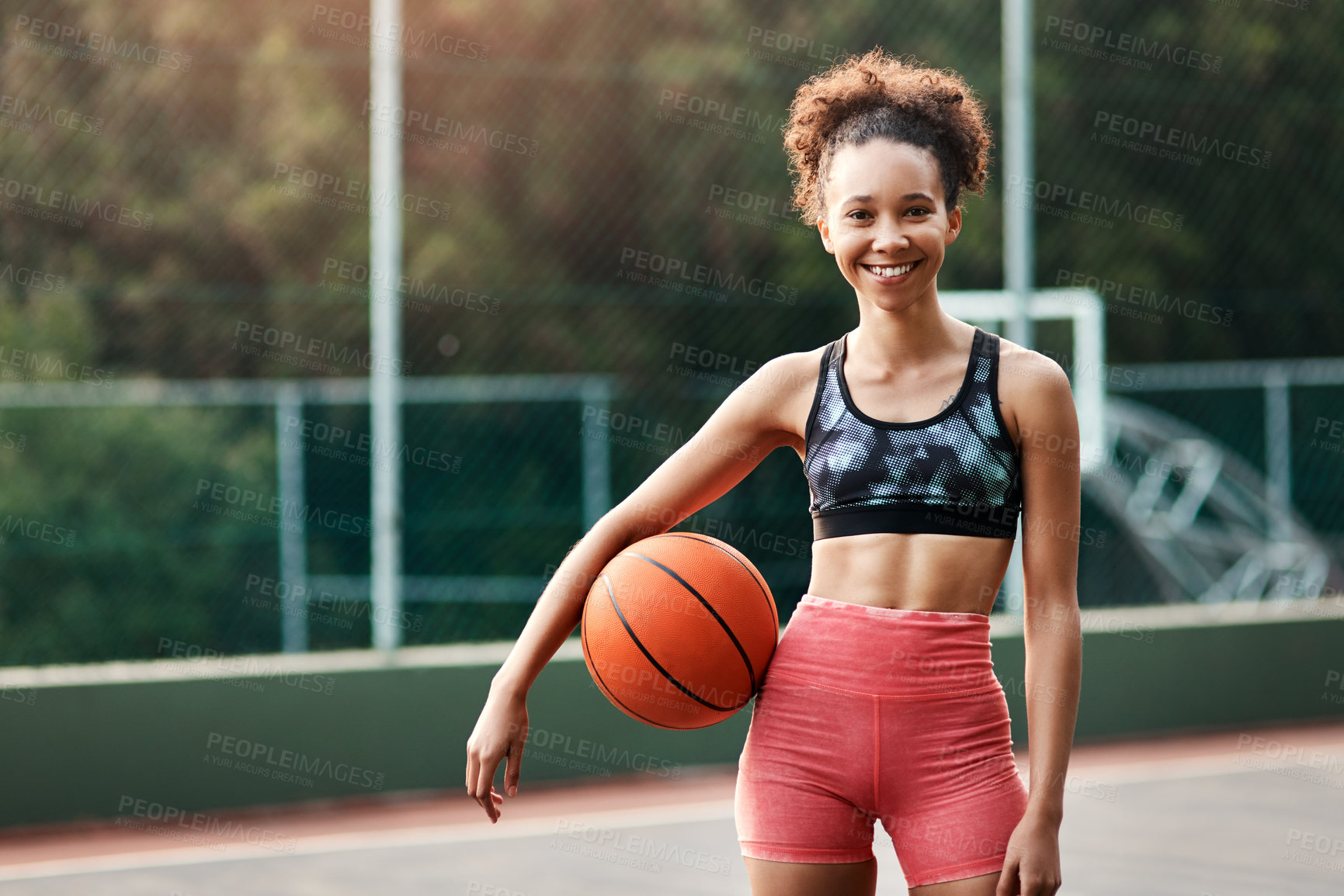 Buy stock photo Cropped shot of an attractive young sportswoman standing on the court alone and holding a basketball during the day