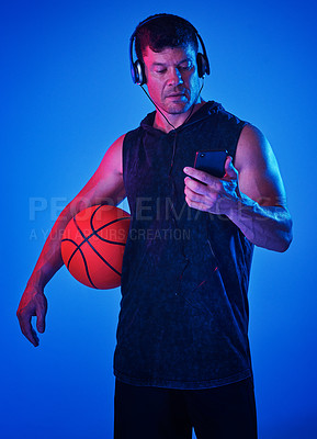 Buy stock photo Blue filtered shot of a sportsman wearing headphones while holding a basketball