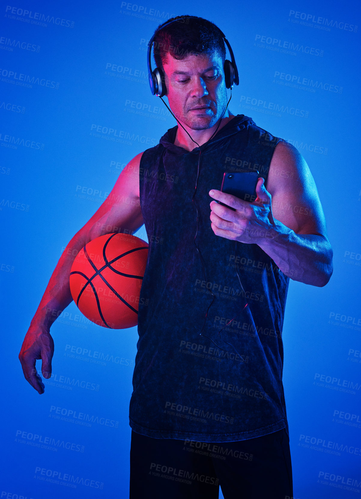 Buy stock photo Blue filtered shot of a sportsman wearing headphones while holding a basketball