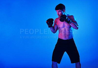 Buy stock photo Blue filtered shot of a sportsman wearing boxing gloves while posing in the studio