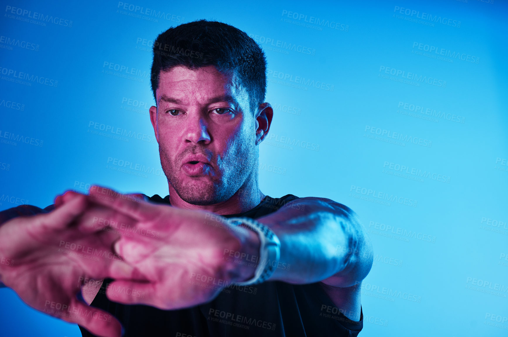 Buy stock photo Blue filtered shot of a sportsman stretching in the studio