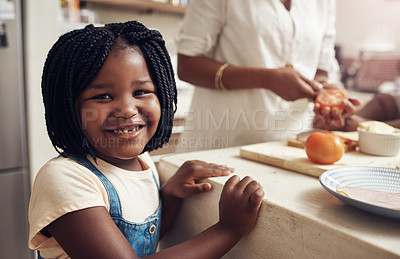 Buy stock photo Portrait of an adorable little girl standing in the kitchen while her mother and baby sister in the background
