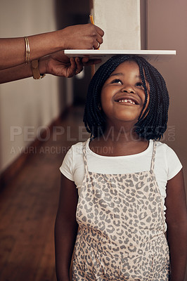 Buy stock photo Cropped shot of a mother measuring the height of her adorable young daughter at home