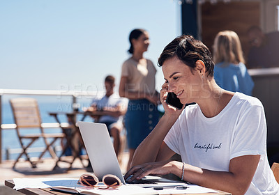 Buy stock photo Cropped shot of a cheerful young woman talking on her cellphone while doing work on her laptop next to a beach promenade outside during the day