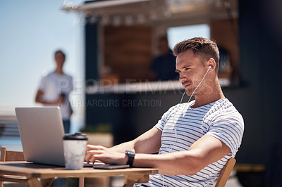 Buy stock photo Cropped shot of a cheerful young man working on his laptop next to a coffee truck outside during the day
