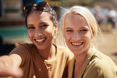 Buy stock photo Portrait of two cheerful young woman taking a self portrait together with a cellphone outside during the day
