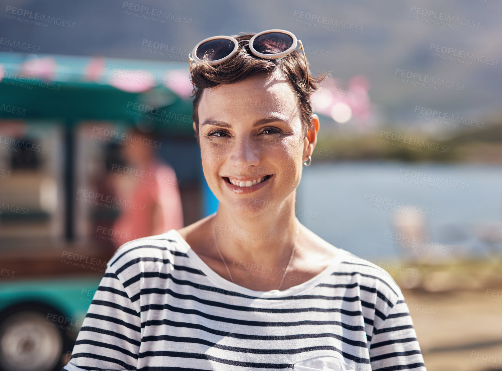 Buy stock photo Woman, portrait and happiness by lake for holiday in nature, freedom or adventure travel for wellness. Female tourist, outdoor and relax on vacation with smile in Canada, sunshine for health by cafe