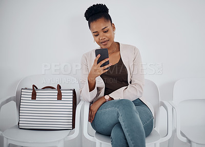 Buy stock photo Shot of a young businesswoman using a cellphone while sitting in a line against a white background