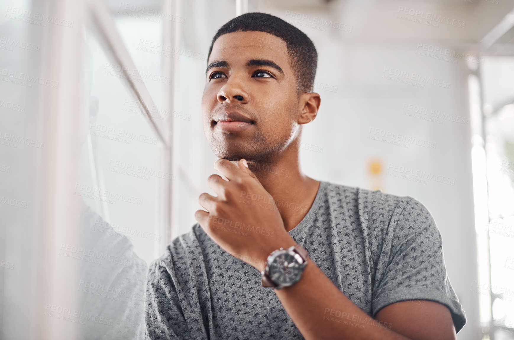 Buy stock photo Shot of a young businessman looking thoughtful while standing in an office