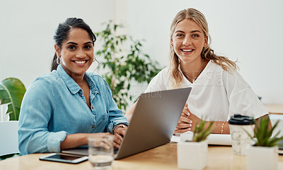 Buy stock photo Cropped portrait of two attractive businesswomen sitting together and using a laptop in the office