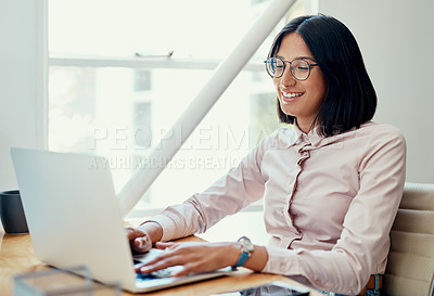 Buy stock photo Cropped shot of an attractive young businesswoman sitting alone and using her laptop in the office