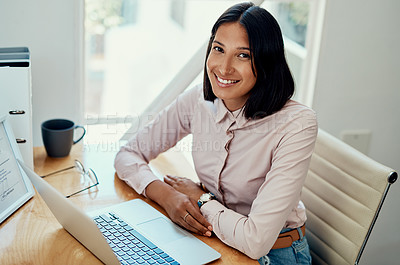 Buy stock photo Cropped portrait of an attractive young businesswoman sitting alone and using her laptop in the office