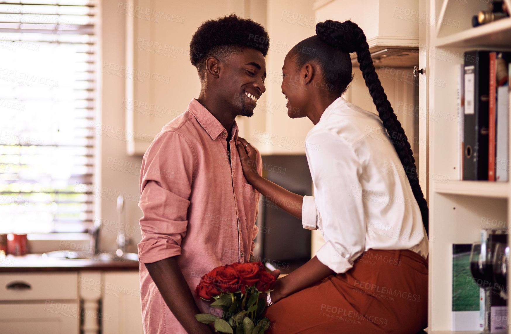 Buy stock photo Cropped shot of an affectionate young man giving his wife a bunch of roses in their kitchen at home