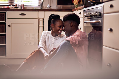 Buy stock photo Full length shot of an affectionate young couple smiling at each other while sitting in their kitchen at home