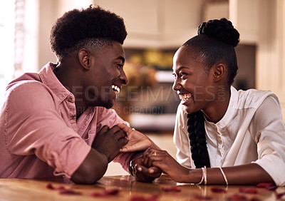 Buy stock photo Cropped shot of an affectionate young couple laughing together while sitting in their kitchen on Valentine's day