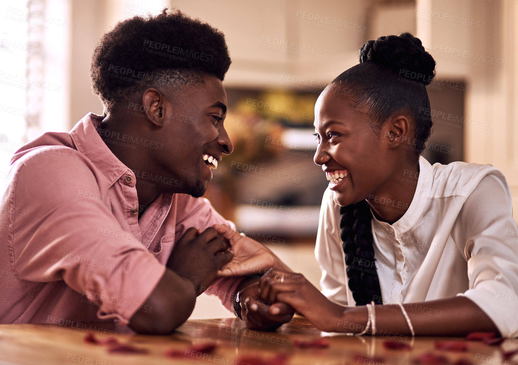 Buy stock photo Cropped shot of an affectionate young couple laughing together while sitting in their kitchen on Valentine's day
