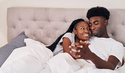 Buy stock photo Shot of a young couple lying in bed together