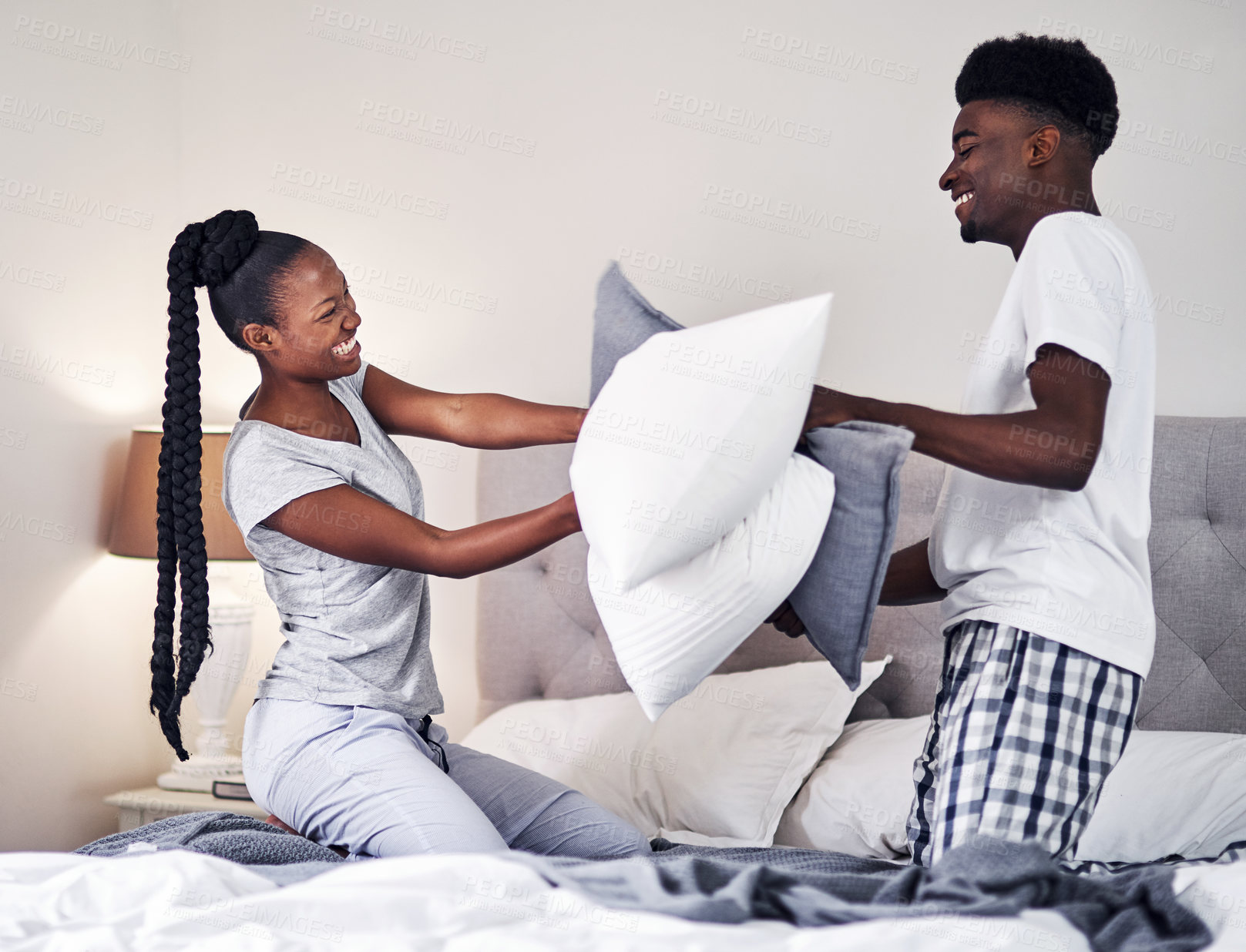 Buy stock photo Black couple, people and happy with pillow fight in bedroom for fun with care, support and bonding. Relationship, love and smile or playful with laughing in bed for trust, games and excited at home