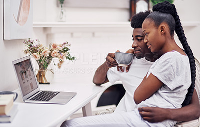 Buy stock photo Shot of a young couple using a laptop while sitting together at home