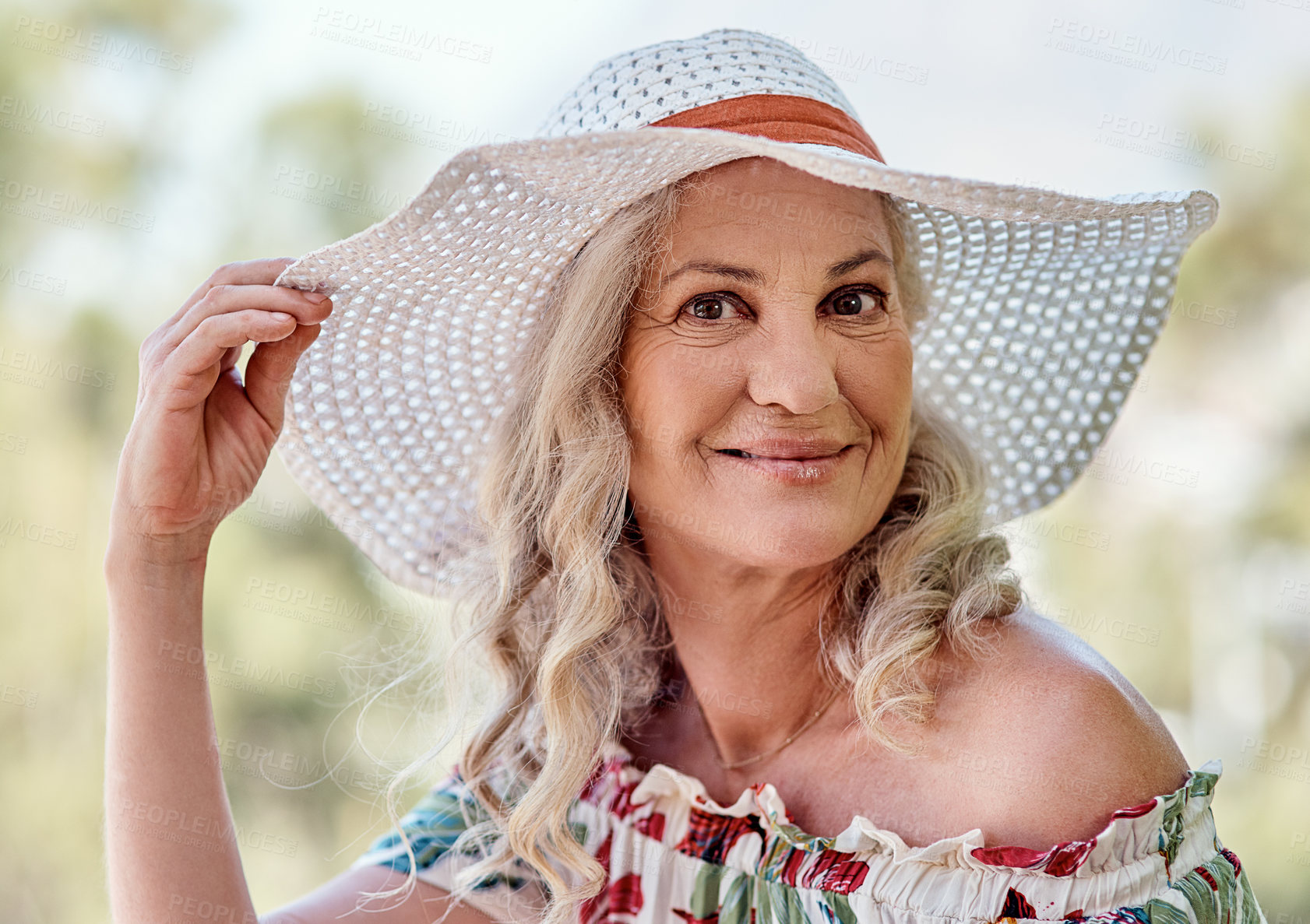 Buy stock photo Cropped portrait of an attractive senior woman wearing a summer hat while standing outdoors