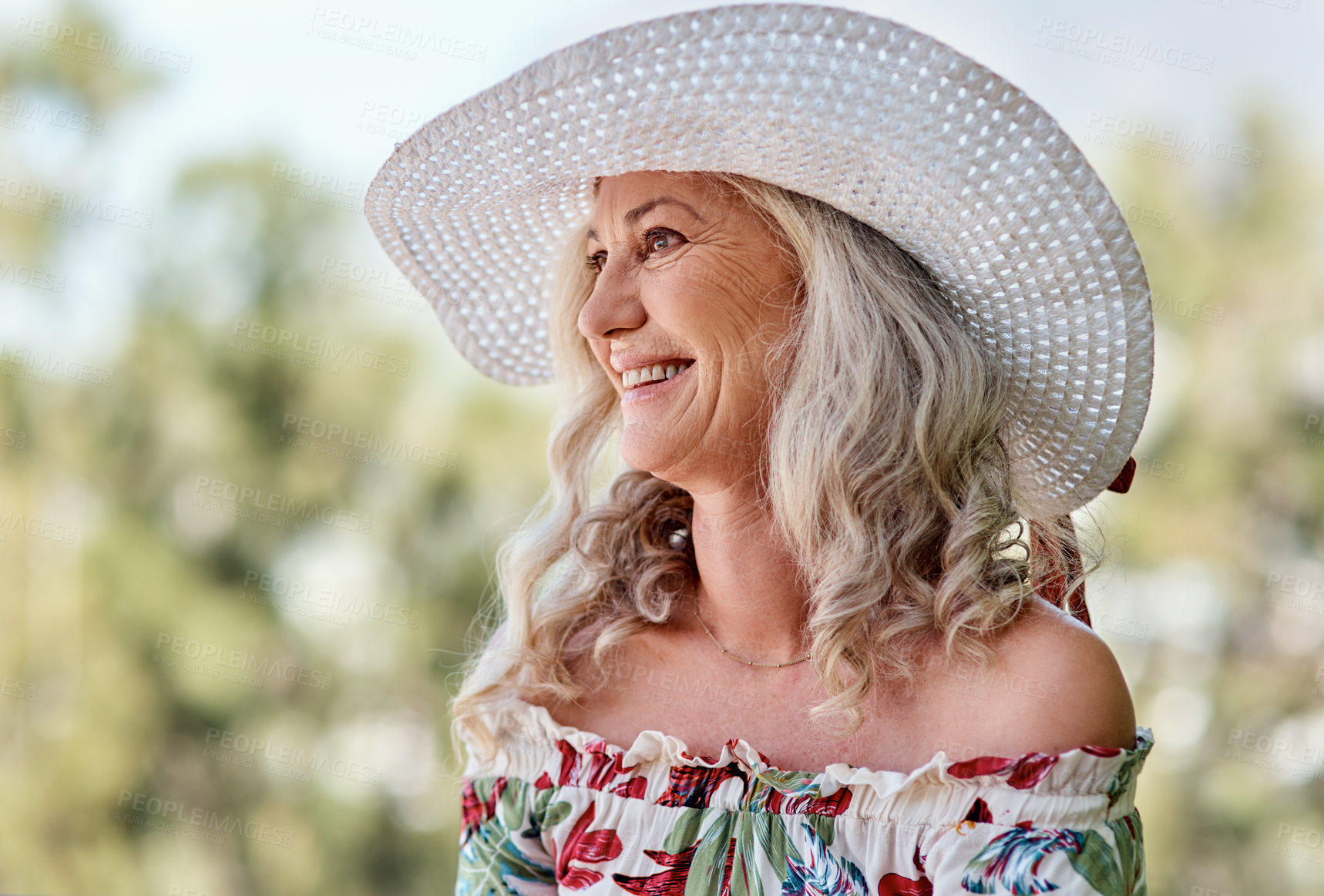 Buy stock photo Cropped shot of an attractive senior woman smiling while sitting outdoors on a summer's day
