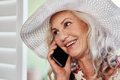 Buy stock photo Cropped shot of an attractive senior woman taking a phonecall while standing indoors at home