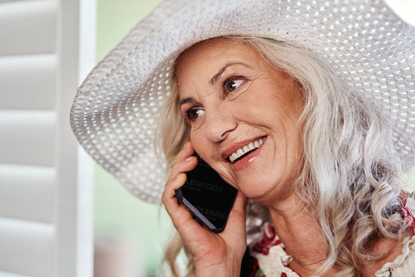 Buy stock photo Cropped shot of an attractive senior woman taking a phonecall while standing indoors at home