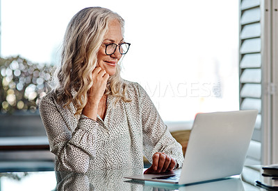 Buy stock photo Cropped shot of an attractive senior businesswoman looking thoughtful while working on a laptop at home