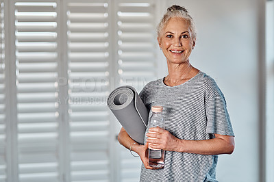 Buy stock photo Portrait of a cheerful mature woman holding a bottle of water and yoga mat ready to start her morning session of yoga inside of a studio