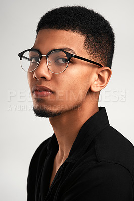 Buy stock photo Portrait of a handsome young man wearing glasses while standing against a grey background  inside of a studio