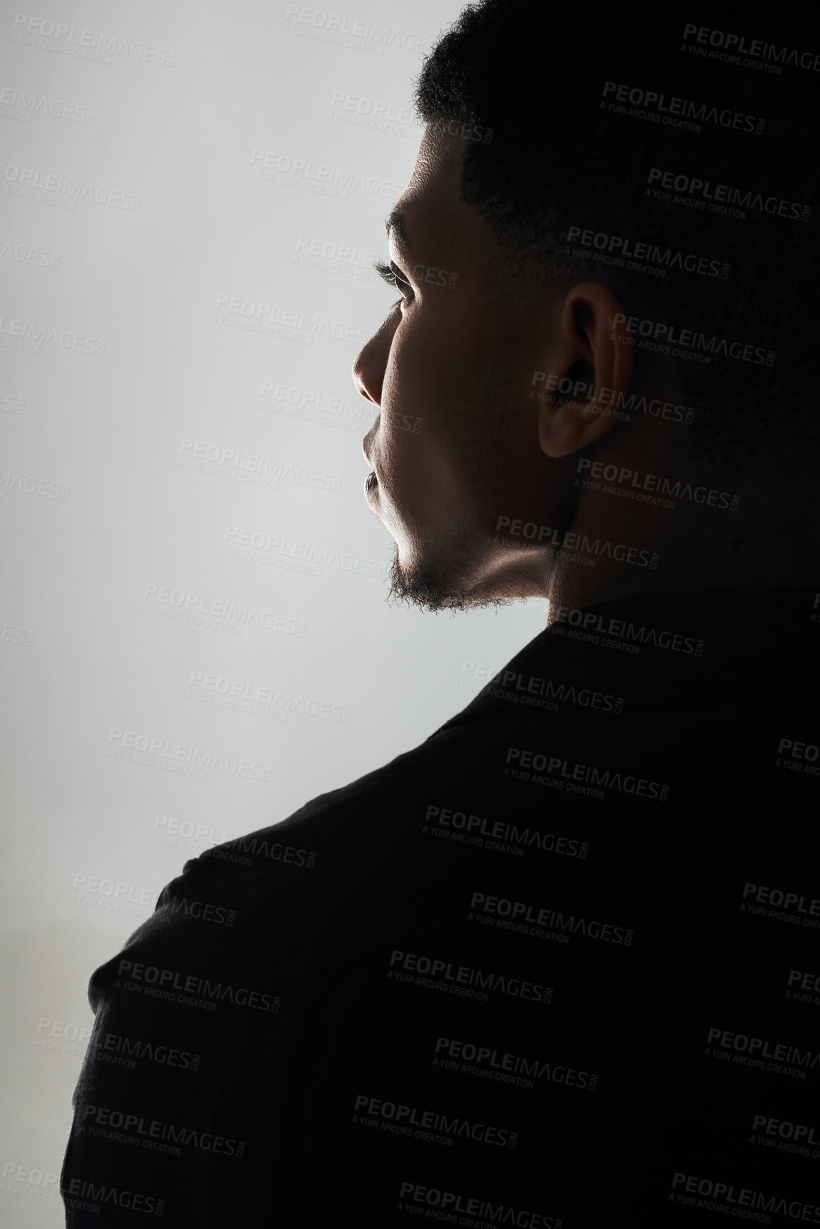 Buy stock photo Rearview shot of a handsome young man posing against a grey background inside of a studio