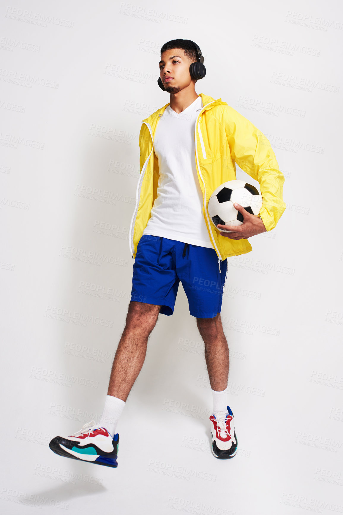 Buy stock photo Man, fashion and soccer player with headphones or ball for music, game or sport on a gray studio background. Young, male person or Italian model with colorful clothing for style, podcast or football