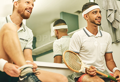 Buy stock photo Shot of two young men getting dressed in the locker room after a game of squash