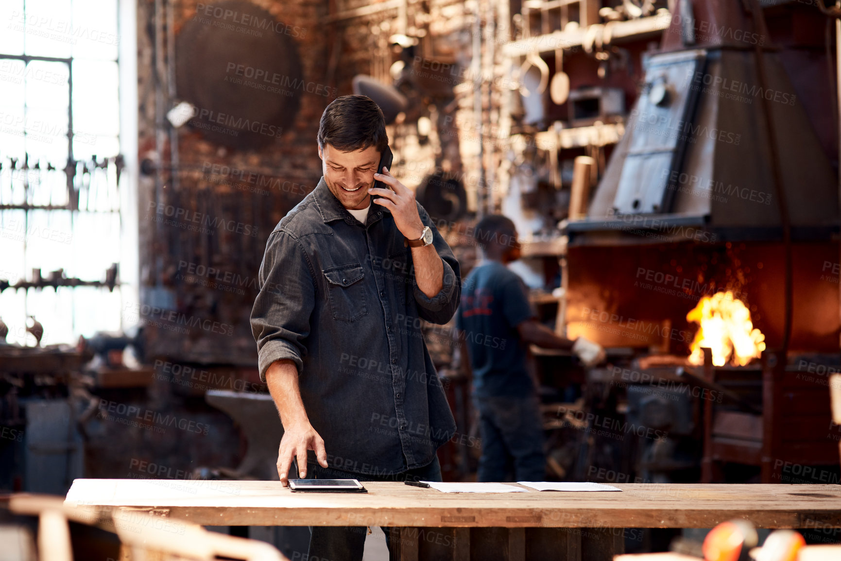 Buy stock photo Online order, phone call and tablet with man in workshop for communication, manufacturing or production. Craftsmanship, forge and planning with happy person at table for industrial metalwork