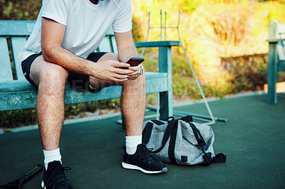 Buy stock photo Tennis, court and man on bench with phone at outdoor competition, exercise and online training schedule. Sports, typing and hands of athlete with smartphone, fitness app and checking game play on web