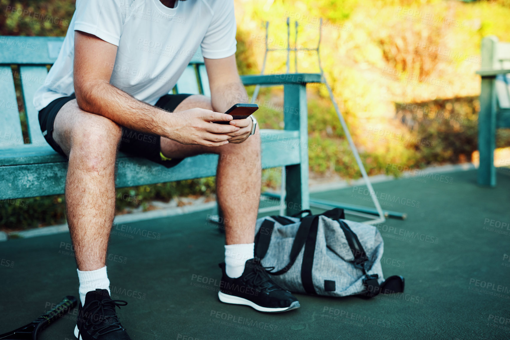 Buy stock photo Tennis, court and man on bench with phone at outdoor competition, exercise and online training schedule. Sports, typing and hands of athlete with smartphone, fitness app and checking game play on web