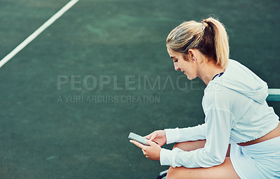 Buy stock photo Shot of a sporty young woman using a cellphone while sitting on a tennis court