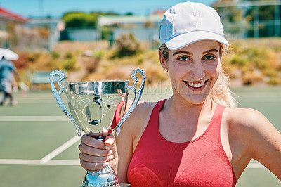 Buy stock photo Cropped portrait of an attractive young woman holding up a trophy after winning a tennis match during the day