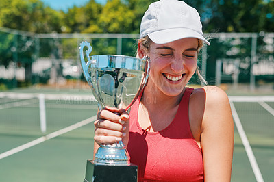 Buy stock photo Cropped shot of an attractive young woman holding up a trophy after winning a tennis match during the day
