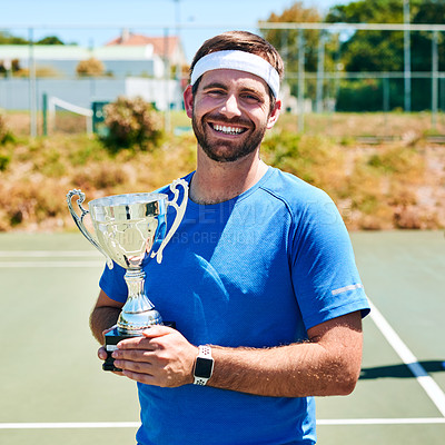 Buy stock photo Cropped portrait of a handsome young man holding up a trophy after winning a tennis match during the day