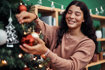 Buy stock photo Shot of a young woman decorating a Christmas tree at home
