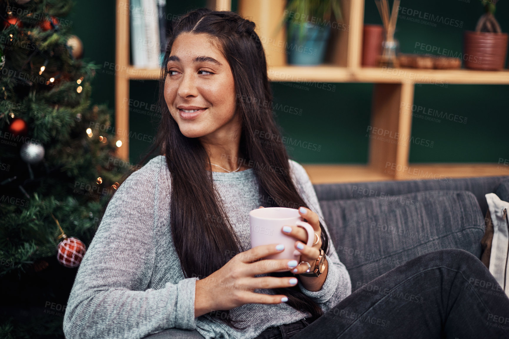 Buy stock photo Shot of a beautiful young woman enjoying a warm beverage on the sofa during Christmas at home