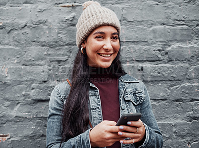 Buy stock photo Cropped shot of an attractive teenage girl standing alone against a gray wall in the city and using her cellphone