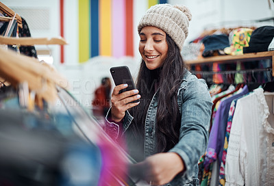 Buy stock photo Cropped shot of an attractive teenage girl standing alone and using her cellphone while in a clothing store alone