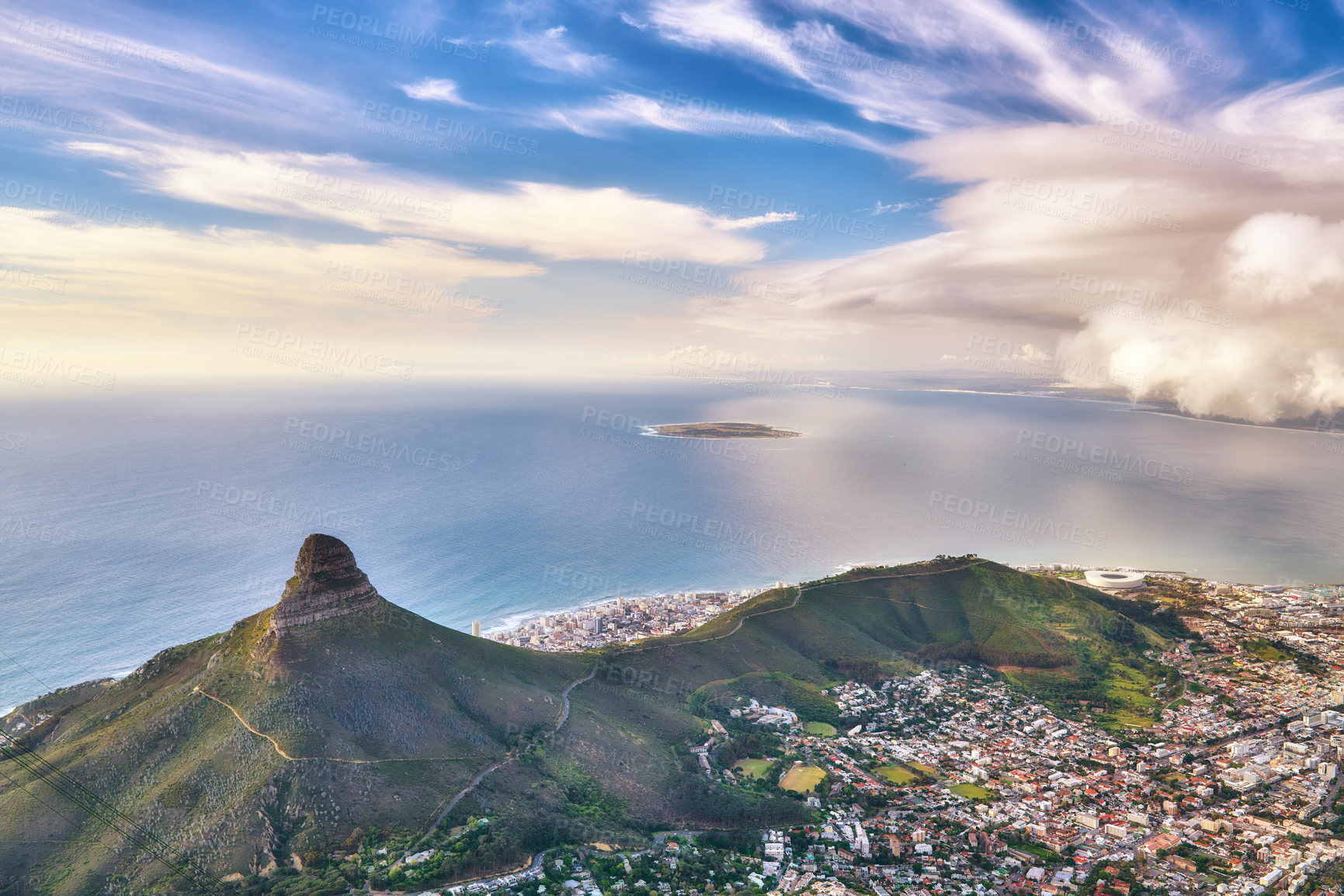 Buy stock photo Aerial view of a mountain and ocean near a coastal city on a cloudy day. High angle of Lions Head in a stunning urban scene near a calm sea. Cape Town from above with a blue horizon and copy space