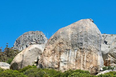 Buy stock photo Rocks and boulders on a mountain peak with green lush bush growing on Lions Head in Cape Town with sky and copyspace. Large area of wilderness landscape with calm fresh air and harmony in nature