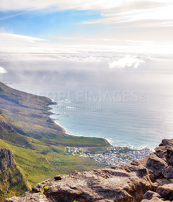 Buy stock photo Landscape of Lions Head mountain with houses, ocean and cloudy sky with copy space. Perspective view of green mountains with lots of vegetation overlooking an urban city in Cape Town, South Africa