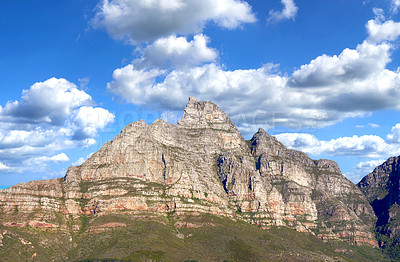 Buy stock photo Landscape of mountains on a blue cloudy sky. Beautiful view of mountain outcrops with hill covered in green grass, shrubs and bushes on popular landmark or hiking location in Cape Town, South Africa 