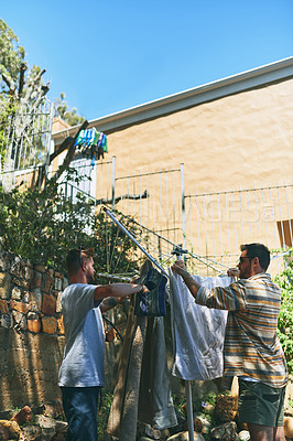 Buy stock photo Cropped shot of two cheerful young men doing the washing together outside in the back garden at home