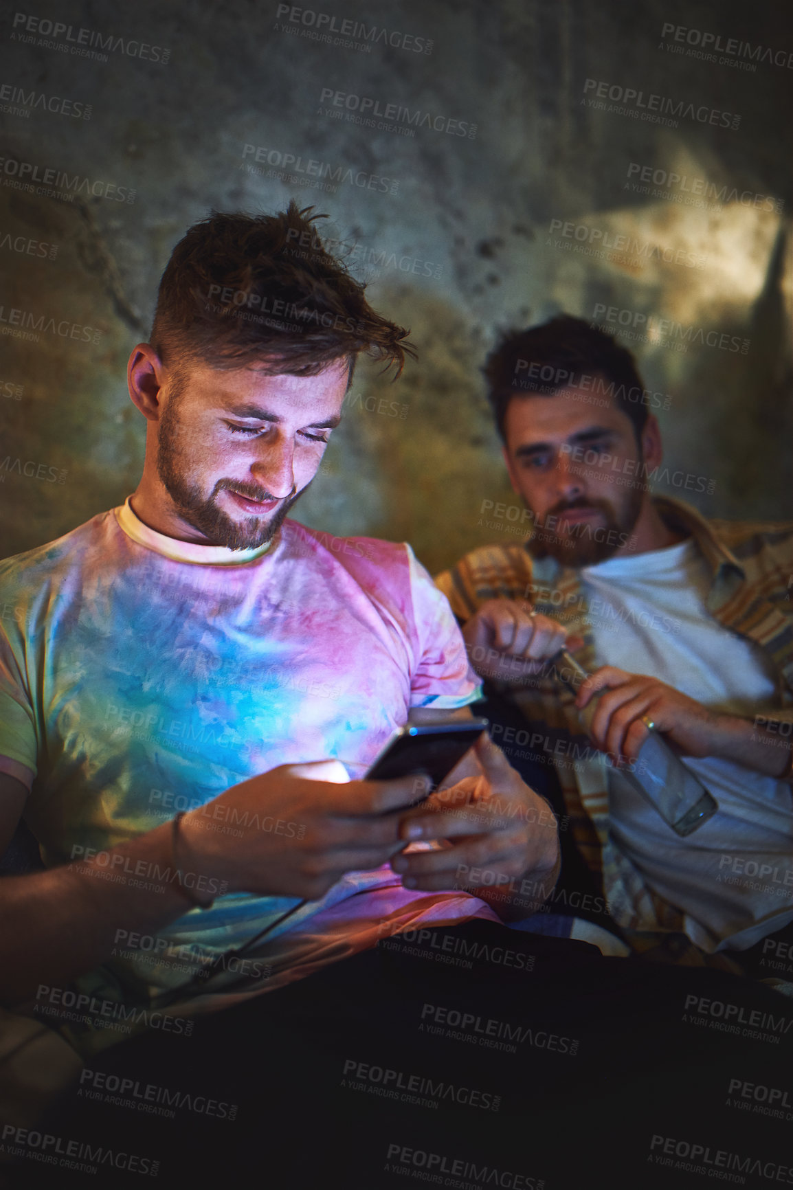 Buy stock photo Cropped shot of two handsome young man using a smartphone while sitting with his friend at home